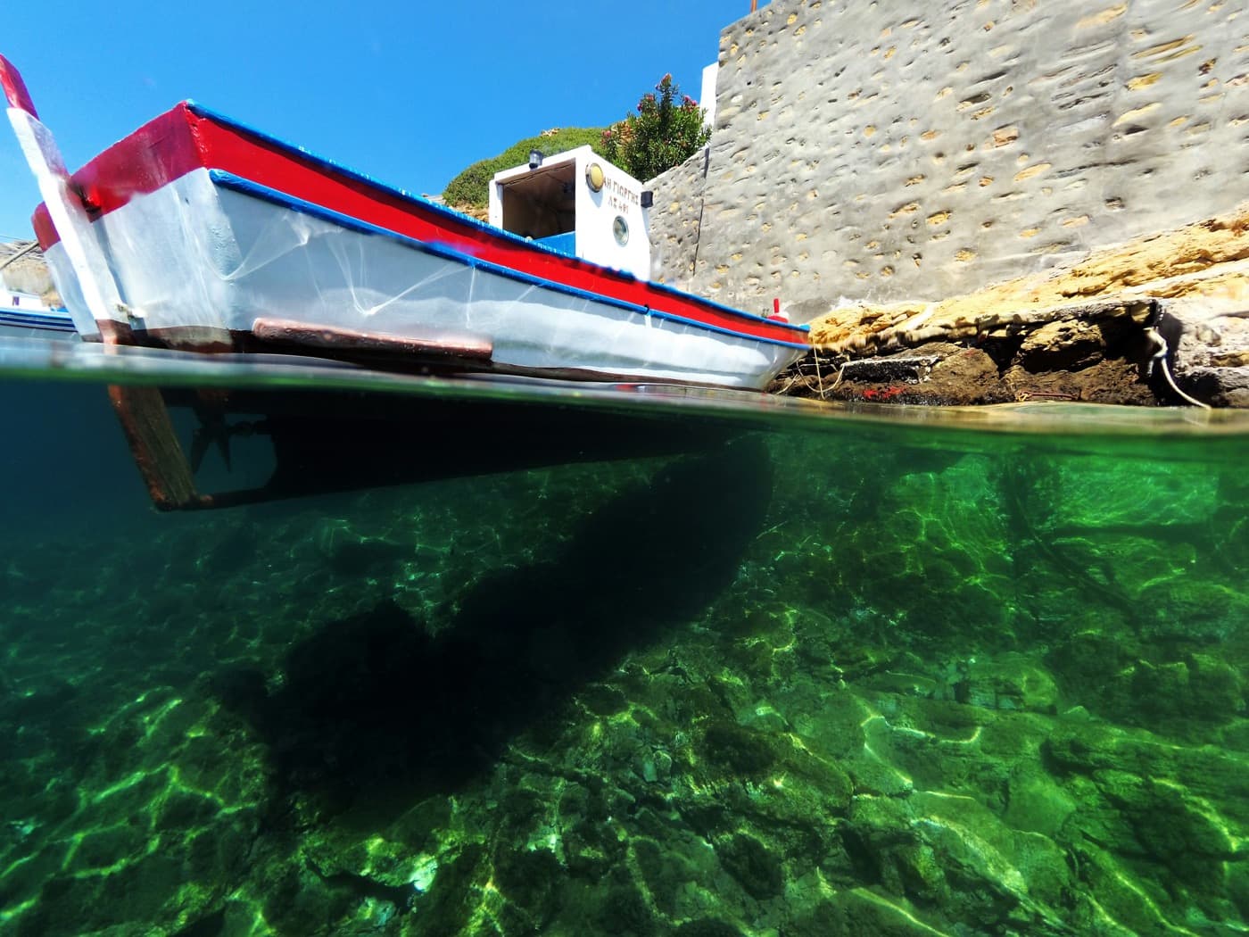 A red and white fishing boat photographed half underwater over emerald water