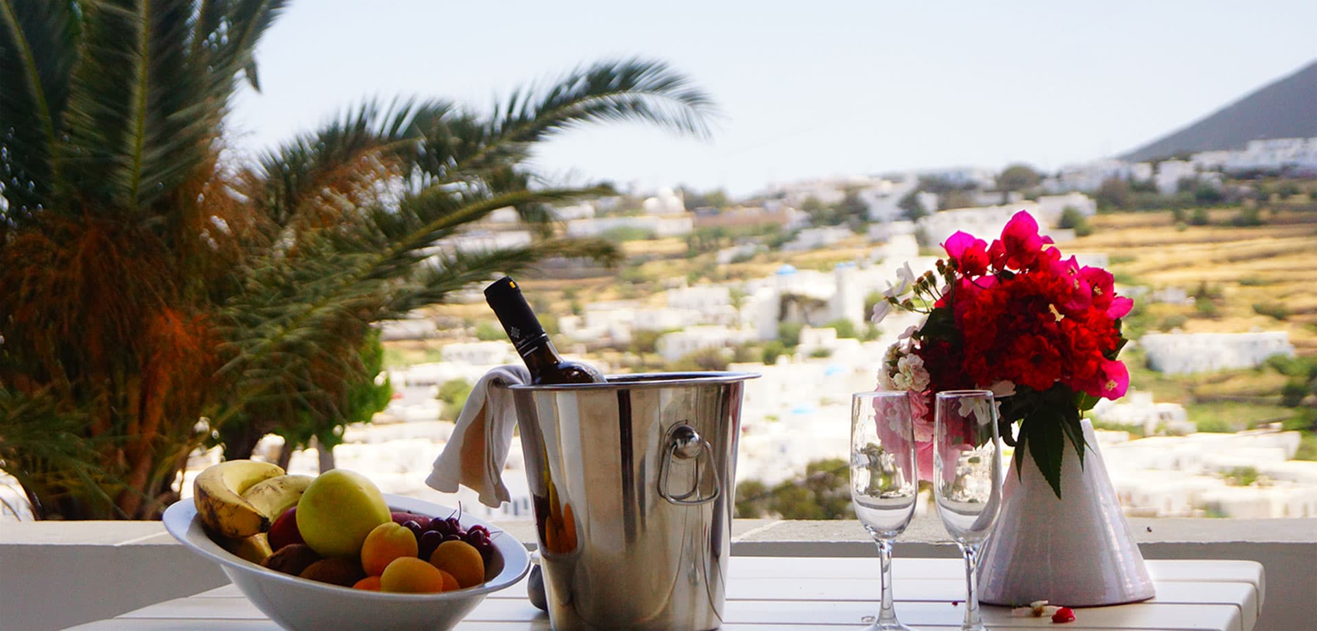 A terrace table with fruit and flowers looking out over the white villages of Sifnos