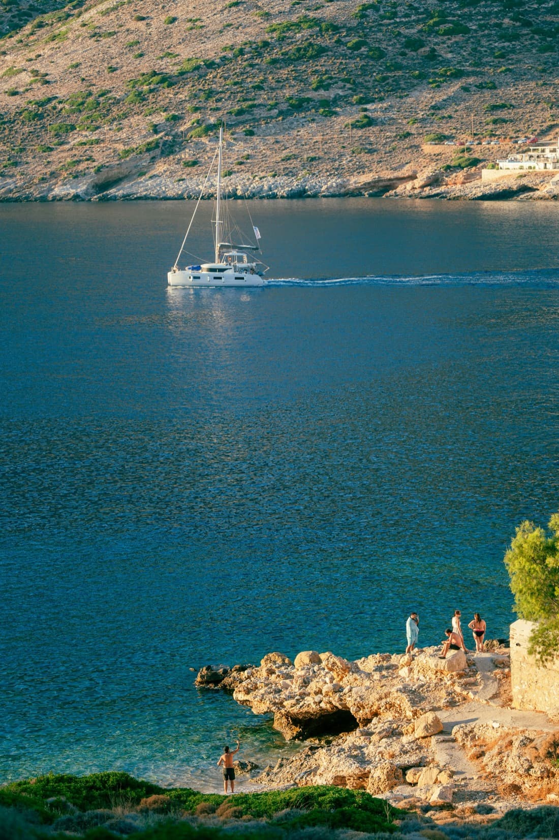 A sailing boat on deep blue water in a Sifnos bay in warm late afternoon light